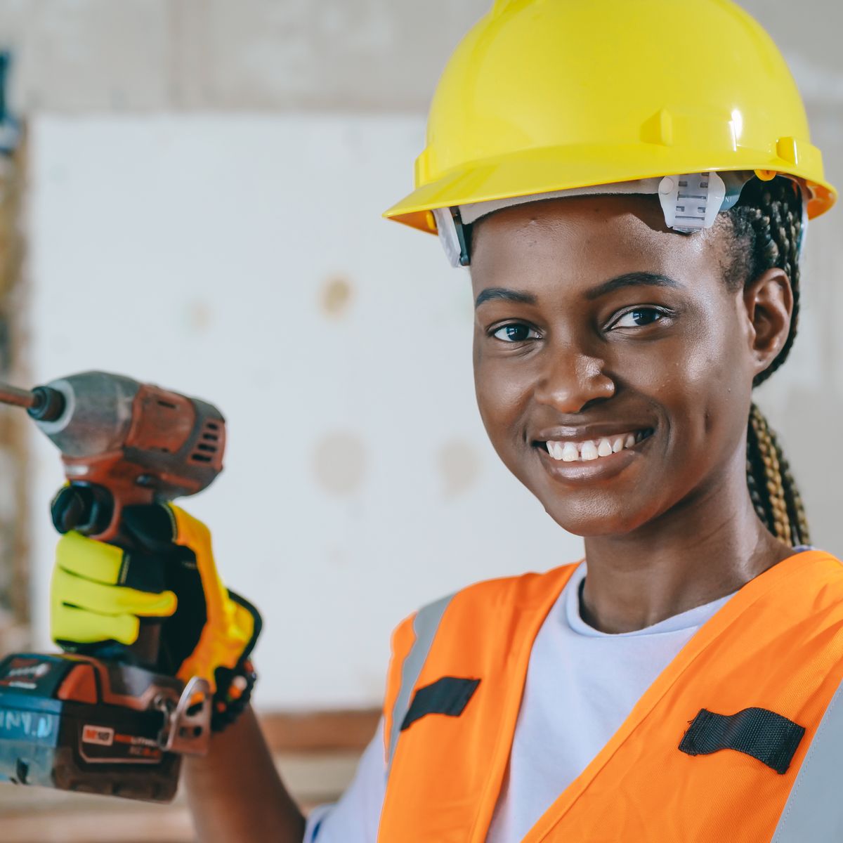A smiling tradeswoman holding a cordless drill