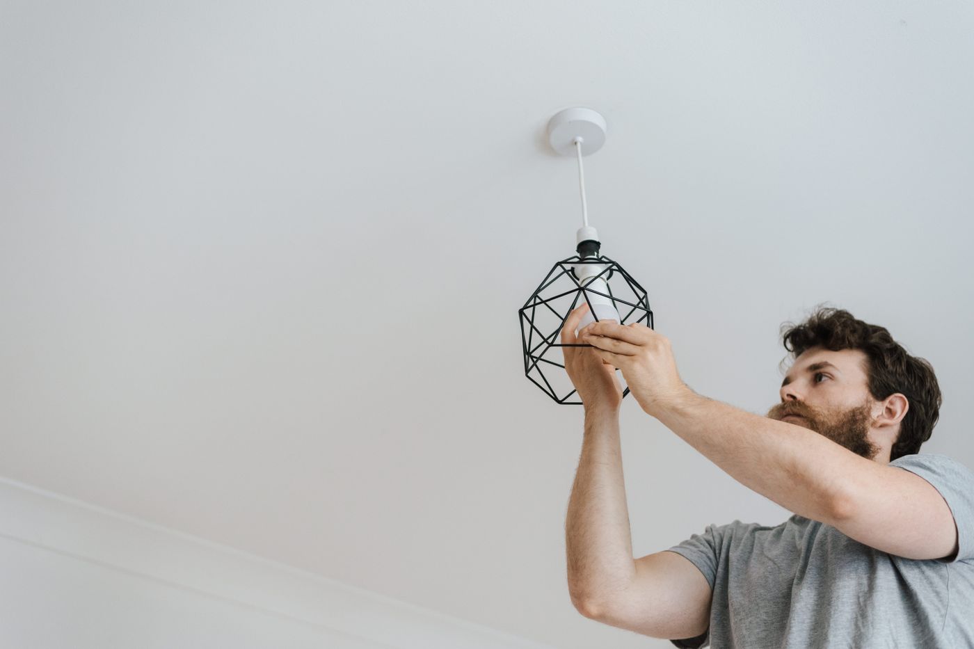 A tradesperson fitting a pendant light in a home
